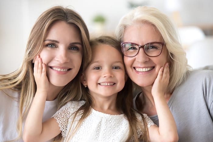 A grandmother, mother, and daughter smiling together